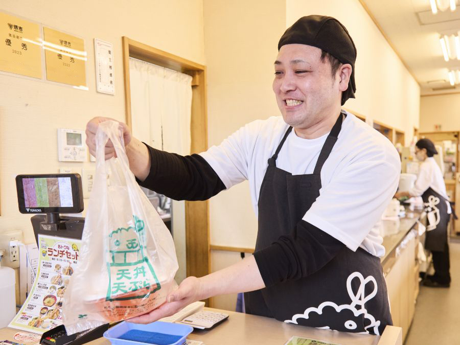 お持ち帰りの料理をお渡しするT.M.さん