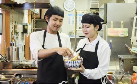 先輩スタッフに盛り付けを教わるスタッフ