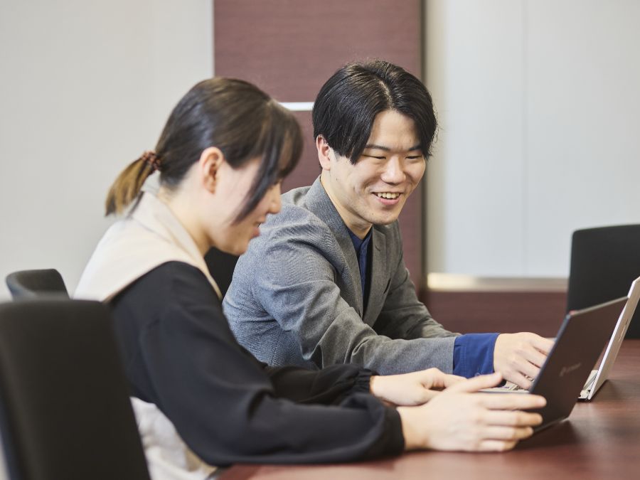 後輩スタッフに笑顔で教えるI.T.さん